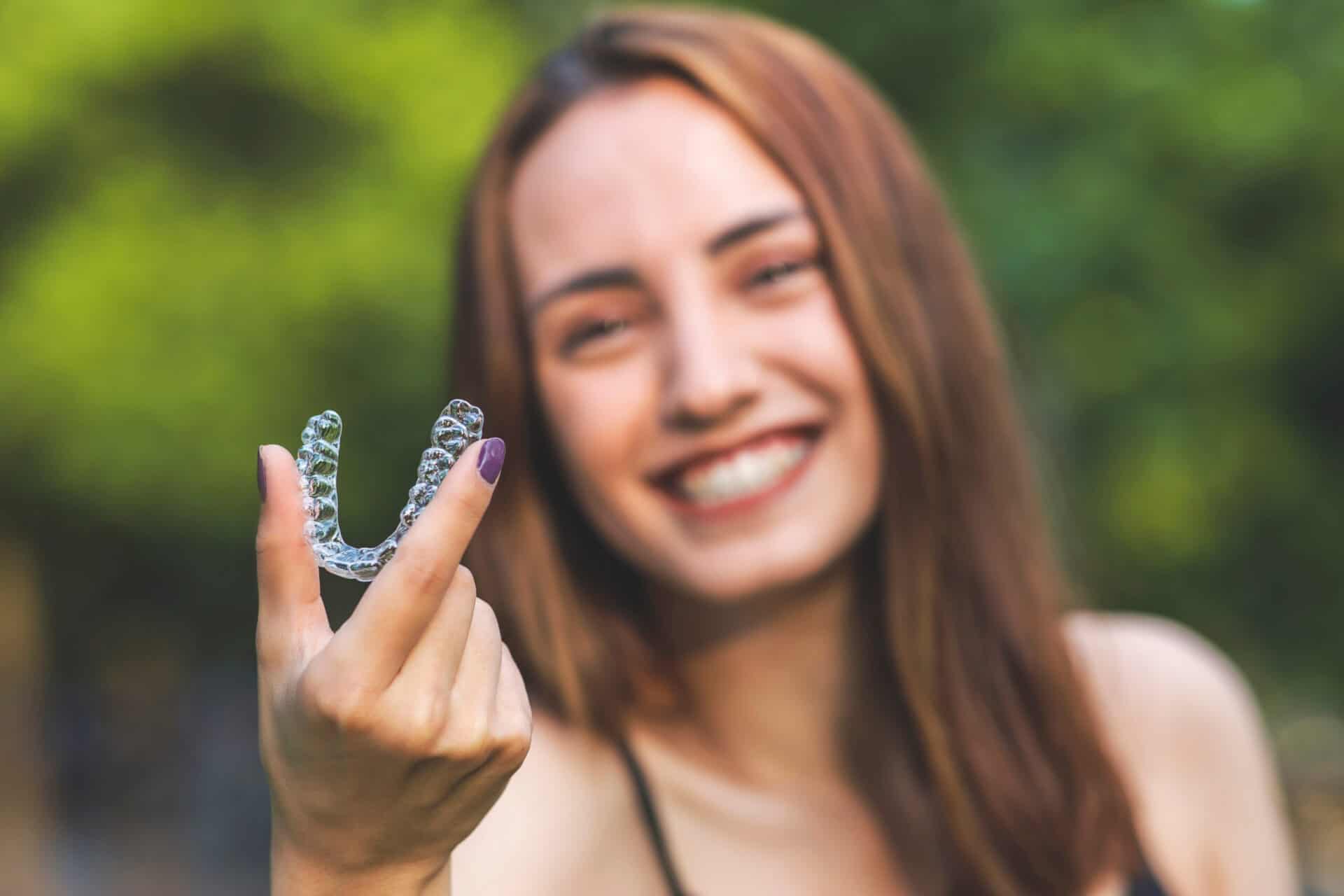 Young woman holding an invisalign brace