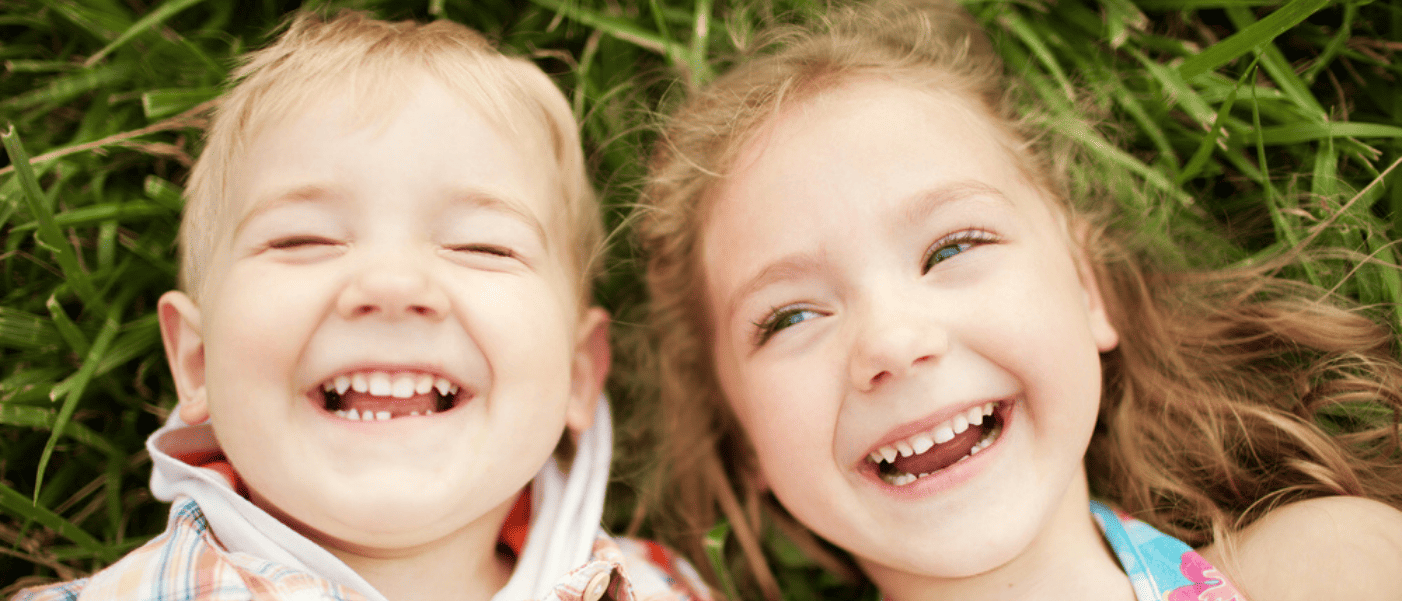 Two smiling children laying in the grass.