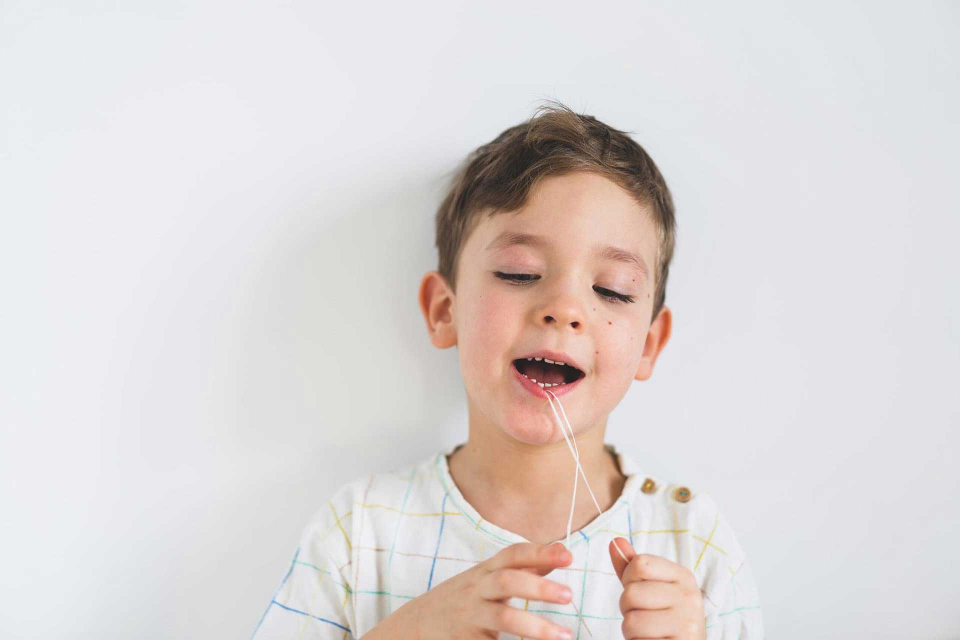 Young boy flossing his teeth
